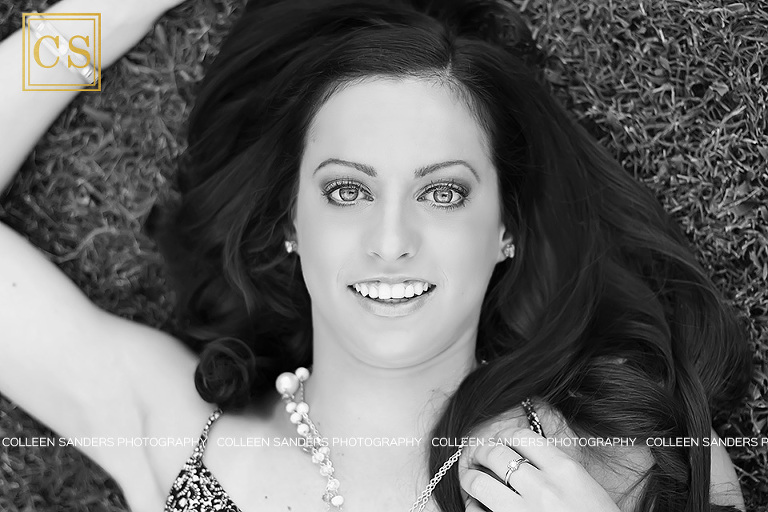 Nicole in a floral romper laying in the grass in black and white by senior photographer Colleen Sanders.